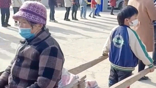 男孩用板车拉着老人排队做核酸