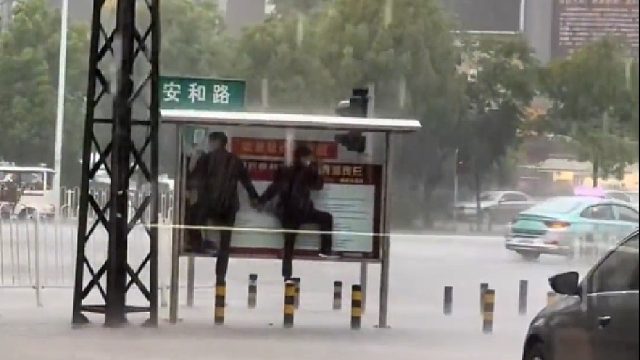 突降暴雨中年夫妻手拉手宣传栏下避雨