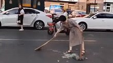 女子主动清扫马路上的玻璃渣，其同伴被气到跳脚