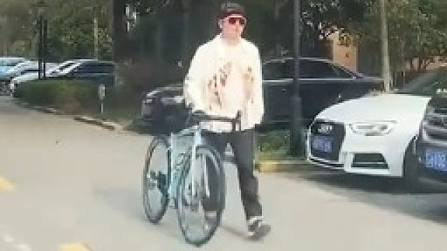 男子牵着自行车在路上行走，遭女司机吐槽是便宜货