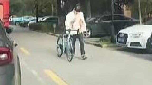 男子牵着自行车在路上行走，遭女司机吐槽是便宜货