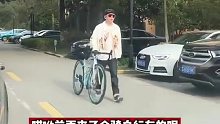 男子牵着自行车在路上行走，遭女司机吐槽是便宜货
