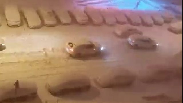 小车在风雪中艰难前行，旁白的车毫无压力开过去