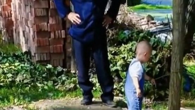 萌娃要去河边玩耍，被好心邻居大爷拴在树上制服。