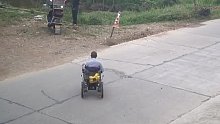老人坐轮椅横穿马路，货车为避让老人撞毁路障。