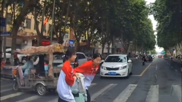 司机斑马线礼让行人，俩女生鞠躬致谢并加快脚步离开