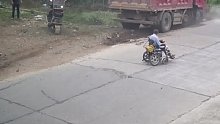 老人坐轮椅横穿马路，货车为避让老人撞毁路障。