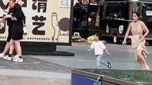 广场上一位年经妈妈追打熊孩子，拎着裙子奔跑差点摔倒