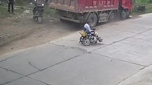 老人坐轮椅横穿马路，货车为避让老人撞毁路障。