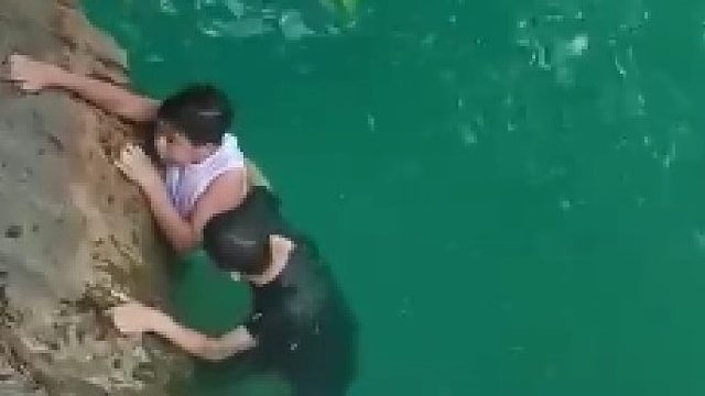 男孩在河边不慎落水，不会游泳的父亲跳到水里营救，路过小伙救起父子俩。