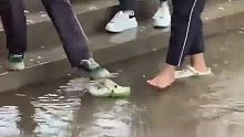 女生怕同学们鞋子湿了，大方将拖鞋变成“共享浮桥”