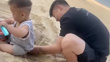 宝爸在宝宝身后挖沙坑娃，看样子爸爸比宝宝玩的带劲啊！