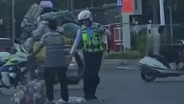 三轮车上的废旧矿泉水瓶不慎散落路中，巡逻交警见状立即上前帮驾驶员收拾