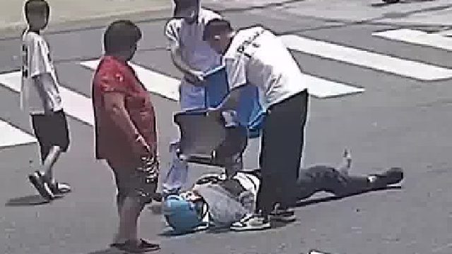 一名外卖小哥骑着电动自行车与一辆小轿车发生碰撞后倒地不起。