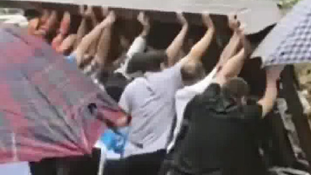 雨天铁栅栏突然倒塌砸中车辆众人合力抬铁栅栏救人，万幸车内被困人员平安救出