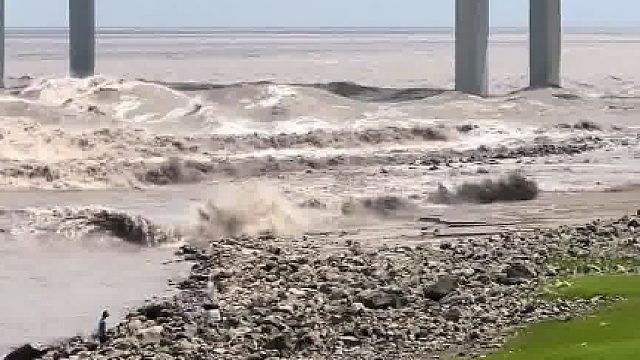 外地游客不知道钱塘江潮水的凶险，竟然在潮水来临时，到危险区域近距离拍潮，幸亏好心人及时呼喊提醒！