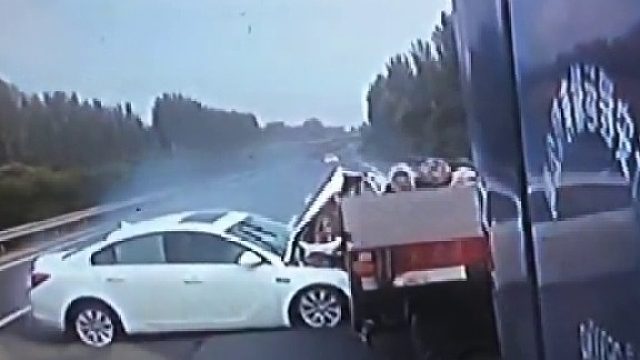 高速上一轿车疑似爆胎撞上卡车，车头卡在卡车底盘，随后被拖行几十米才停下