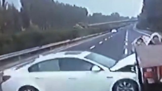 高速上一轿车疑似爆胎径直撞向运货卡车，车头卡在车底盘被拖行几十 米！