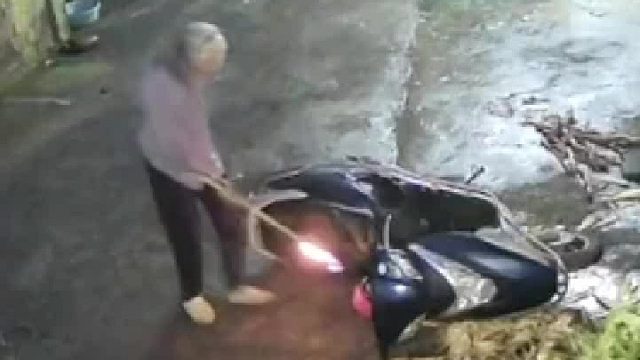 院里的摩托车倒了，老人拿着火把去查看，不慎将漏在地上的汽油点燃。