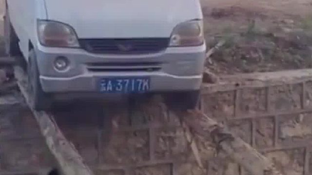 老司机开车从两根木头上过沟