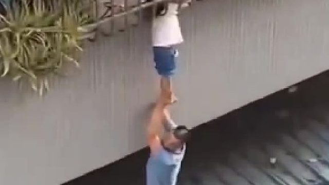 女孩头卡防盗窗身体悬空，两名邻居大哥爬上顶棚，托举孩子