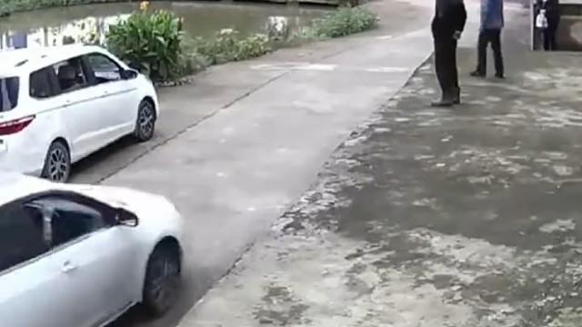 白车拐弯操作失误落水，附近居民迅速施救将人救起。