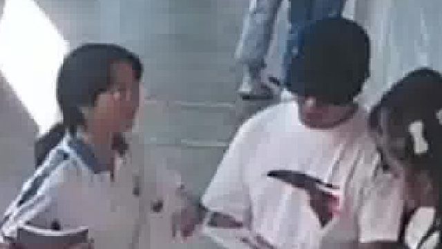 老师在给学生讲题，一个女生过来恶作剧，把他的帽子给掀翻了