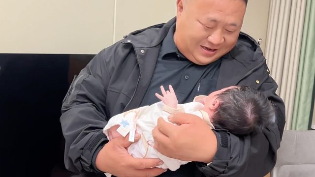 老爸忙里偷閑去看孫女，還特意打扮盛裝出場，父母臉上洋溢著愛意