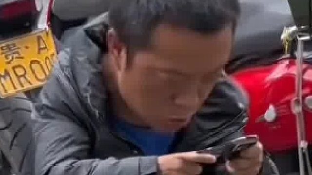 男子在街头坐背兜上打游戏，生意来了是挂机还是接活啊？