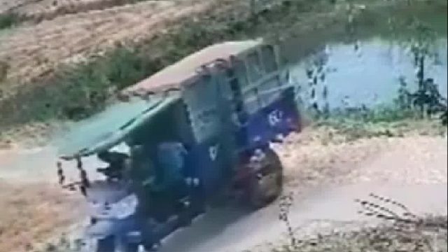 三轮车驾驶员把车倒进水塘里！