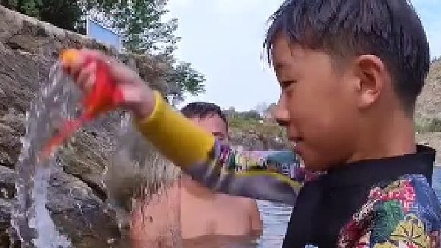 小男孩溜鱼。扔出去的鱼又马上游回到孩子身边，感觉真的很神奇啊