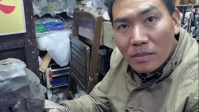 一位来自香港的女士来内地旅游，很想念父亲，于是拿出手机，让老板给她父亲塑像，最后成品惟妙惟肖