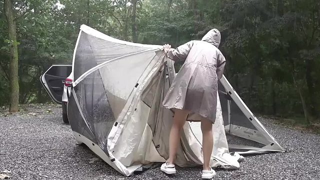 一个人在野外汽车旁搭建帐篷过夜