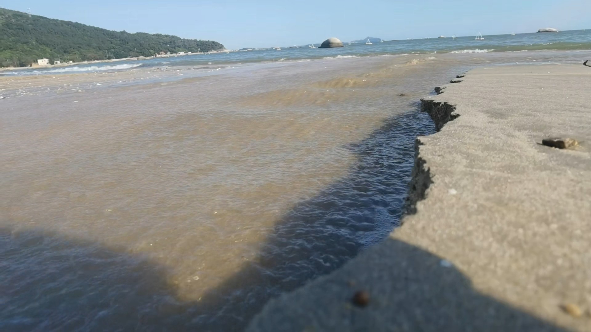 阳光洒在海滩上，水流顺着沙滩的纹理，一路奔腾向大海。