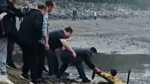 男孩河边玩耍时，不慎陷入淤泥无法脱身。一群大哥看到后上前施救！