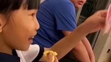 妈妈拿一把不同面额纸币让儿女抽奖，女儿摸到百元时爸爸在旁边眼神暗示成功抽中