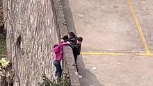 小女孩挂在围墙外危急万分，俩男孩紧紧抓住不放手，“为两位男子汉点赞”