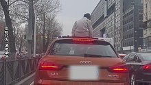 等待信号灯时孩子钻出天窗坐在车顶，拍摄者：家长并未制止