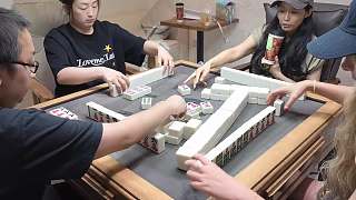 麻將局中女士被逗笑掩面