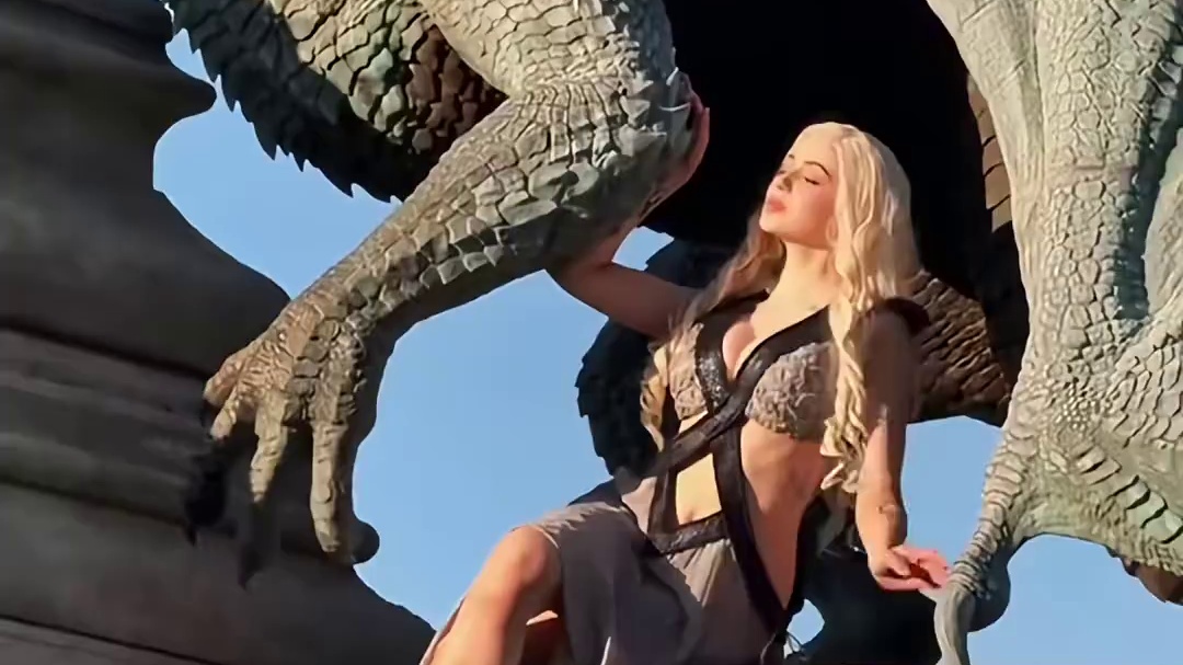 《权力的游戏》中丹妮莉丝·坦格利安的角色扮演cosplay - 角色背景：丹妮莉丝是该剧中的核心人物之一，有着“龙之母”的称号，拥有三条巨龙，是维斯特洛大陆坦格利安家族的后裔，以复国和解放奴隶为重要剧情线。 - 画面呈现：视频中人物的金色长发、服饰风格，以及身旁的巨龙元素，都高度还原了丹妮莉丝的形象特点，营造出剧中的奇幻史诗氛围。