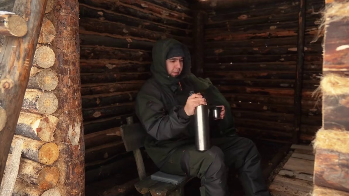 冬季露营木屋被雪覆盖，一个人在里面改造小屋。