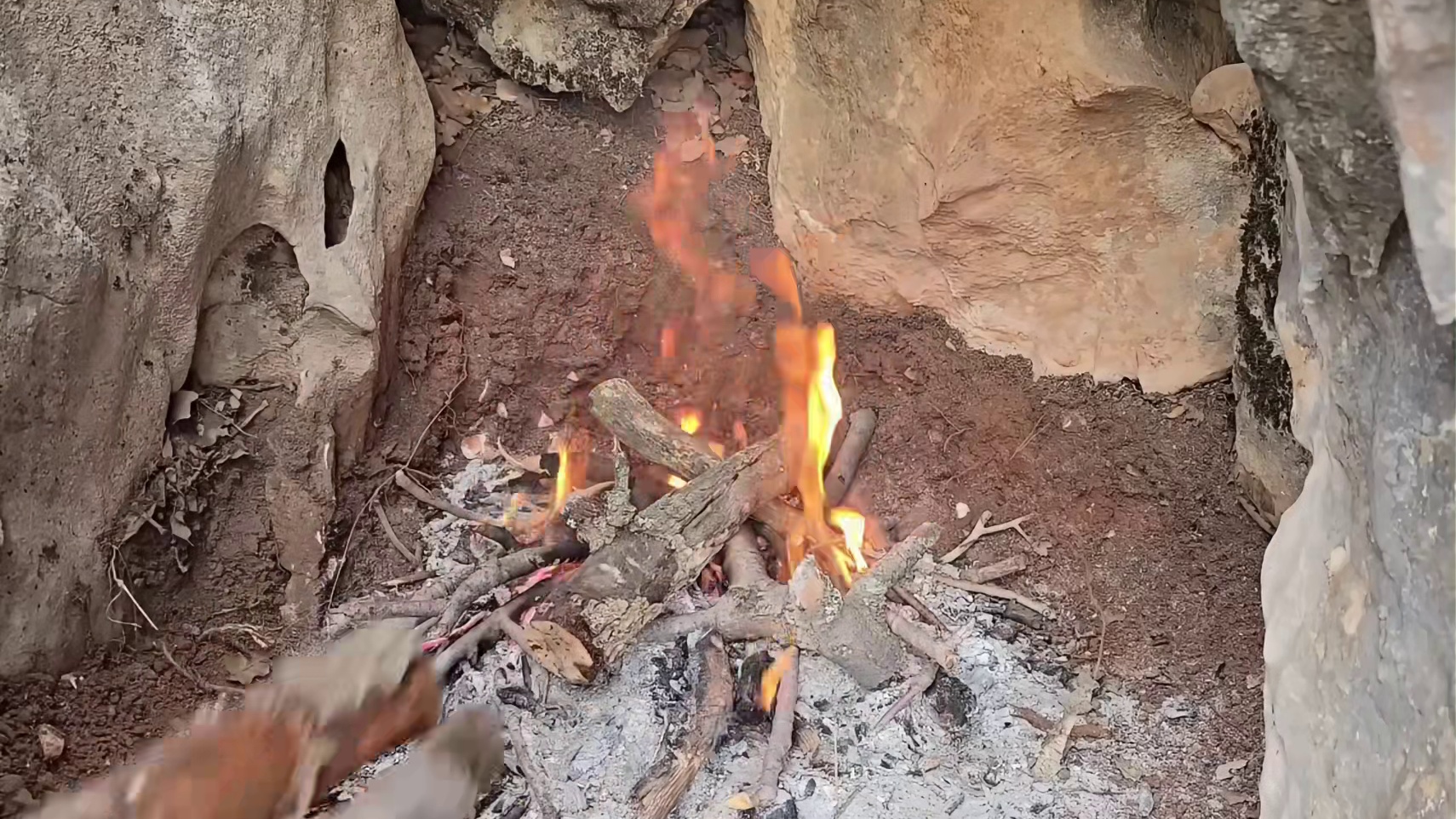 大雪纷飞的野外，男人在两个巨石间搭建了舒适的小屋