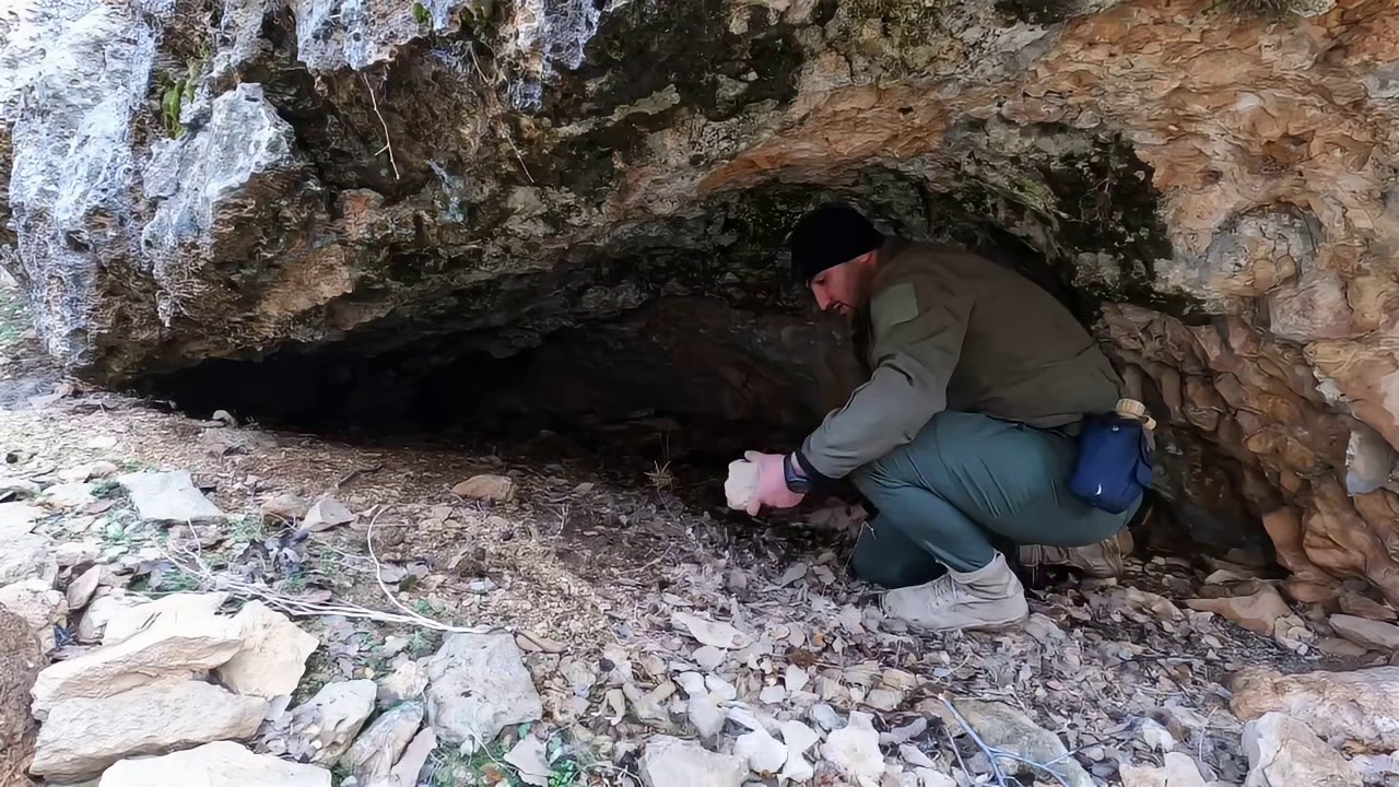 男人在一块巨石下面，给自己搭建了带壁炉的小屋