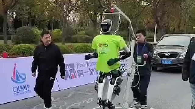 国产机器人参加马拉松测试，工作人员推铁架子全程跟随