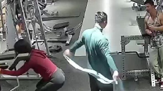 男子在健身房，意外用带子勒住身后女子的脖子。