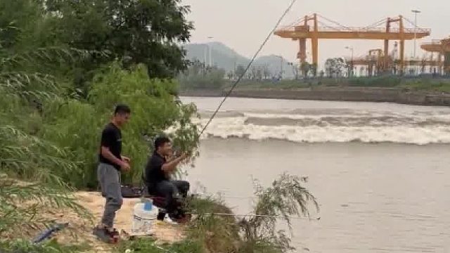 俩小伙在河边钓鱼，突遇涨潮，没见过潮水的他们有点懵！