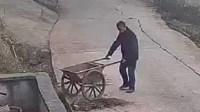 推车大叔在自家门前铲土 结果婚车经过时直接把斗车给撞翻了