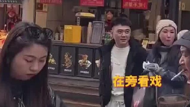 路边买耙耙柑，周围四位工作人员举着喇叭提醒女生