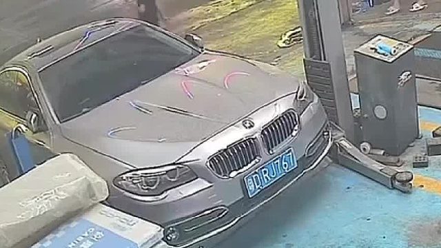 修车店老板关错卷帘门，差点下坠压扁汽车。幸好及时发现，飞奔而出按下暂停开关。