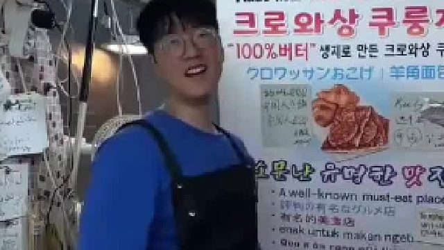 韩国小哥开心地向游客介绍美食，其实旁边的中文是吐槽语！